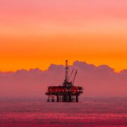 an oil rig in the middle of the ocean at sunset